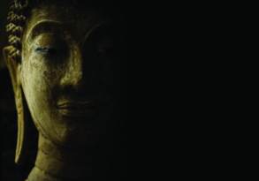 Close-up of a buddha statue's face in shadow with emphasis on serene expression and detailed texture, enhanced by shadow illumination.