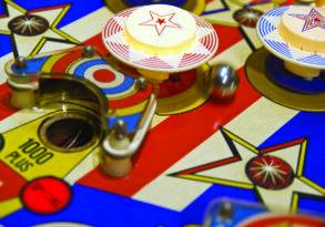 Colorful close-up of vintage pinball wizardry featuring vibrant stars, spinning bumpers, and a detailed playfield.