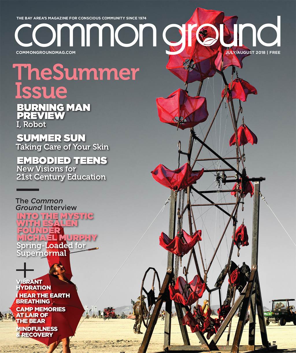 Cover of Common Ground magazine's August 2018 issue, featuring a futuristic robot sculpture at a desert festival, with a clear blue sky in the background.