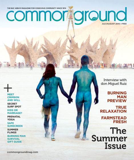 Cover of "common ground" magazine from July 2010, featuring a couple with blue metallic body paint walking hand-in-hand on a beach toward a large, abstract wooden sculpture.