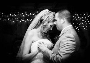 A bride and groom share a close, tender moment during their first dance, surrounded by soft lighting and bokeh, epitomizing the virtues of love.