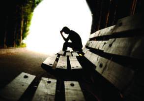 Silhouetted figure sitting on a park bench, head resting in hands, surrounded by trees and soft light, conveying a mood of contemplation or personal growth.