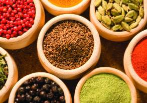 Assortment of colorful spices that have been integral to humankind, displayed in small bowls on a textured surface.