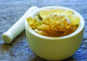 A small white mortar filled with frankincense resin for aromatherapy on a wooden surface.