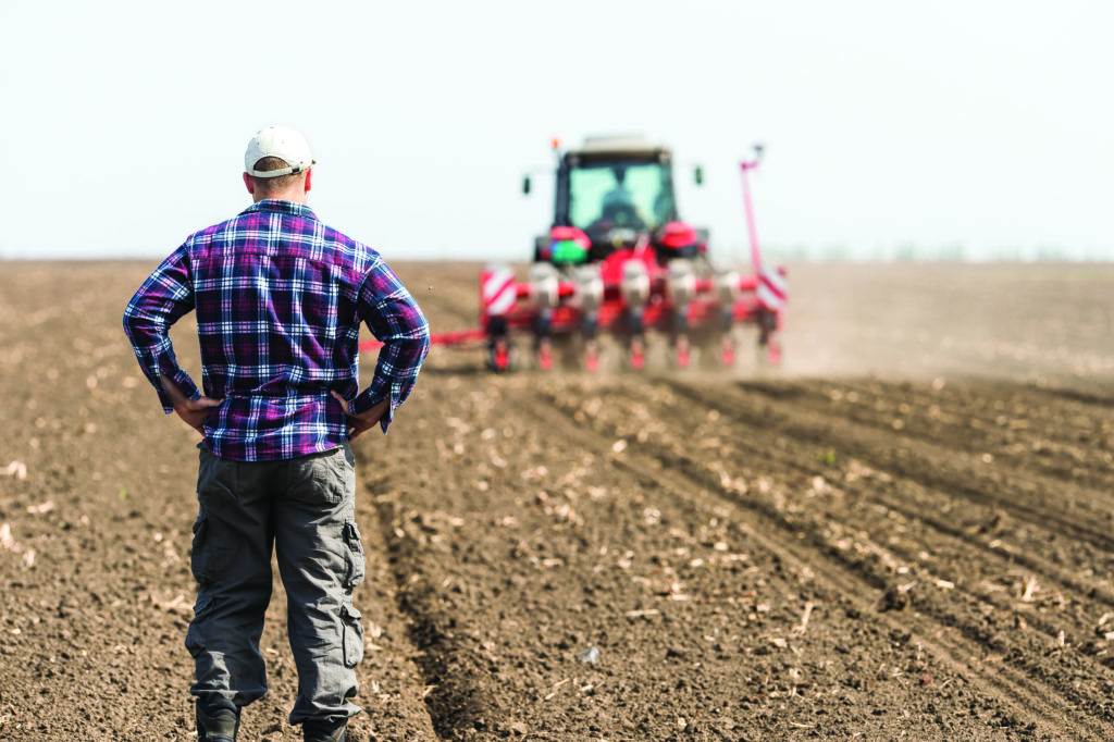 young farmer on farmland with tractor in background