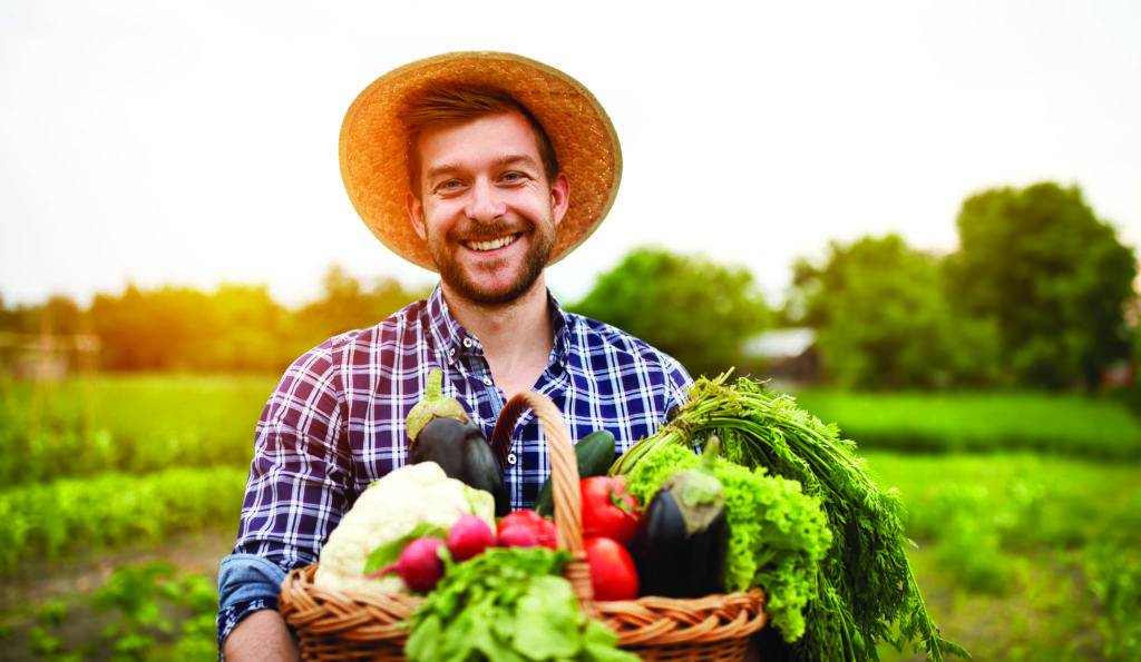 Cheerful farmer with organic vegetables in garden