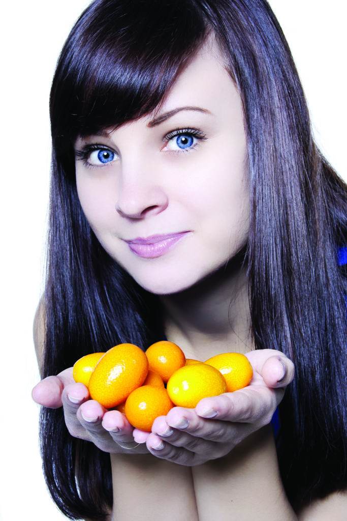 girl holding small tangerines in her hands