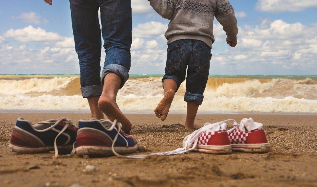 father and his son are walking along the coast