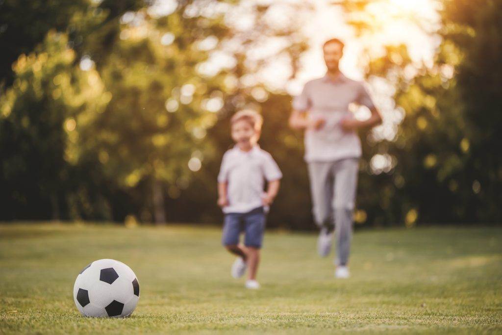 father and son playing football